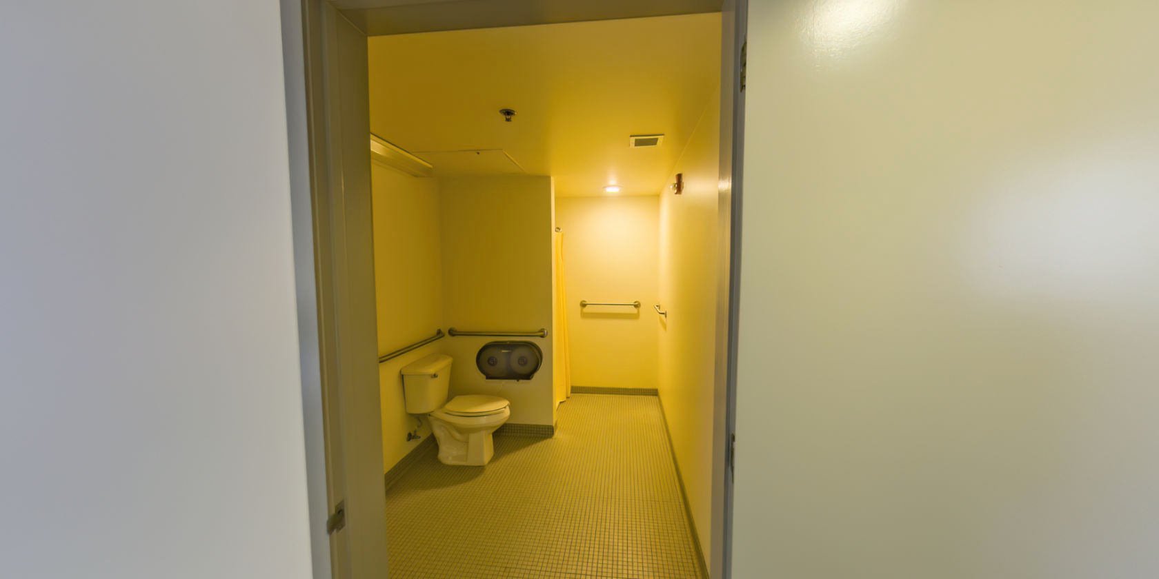 This second bathroom has a tiled floor, a single vanity, and an accessible roll-in shower.