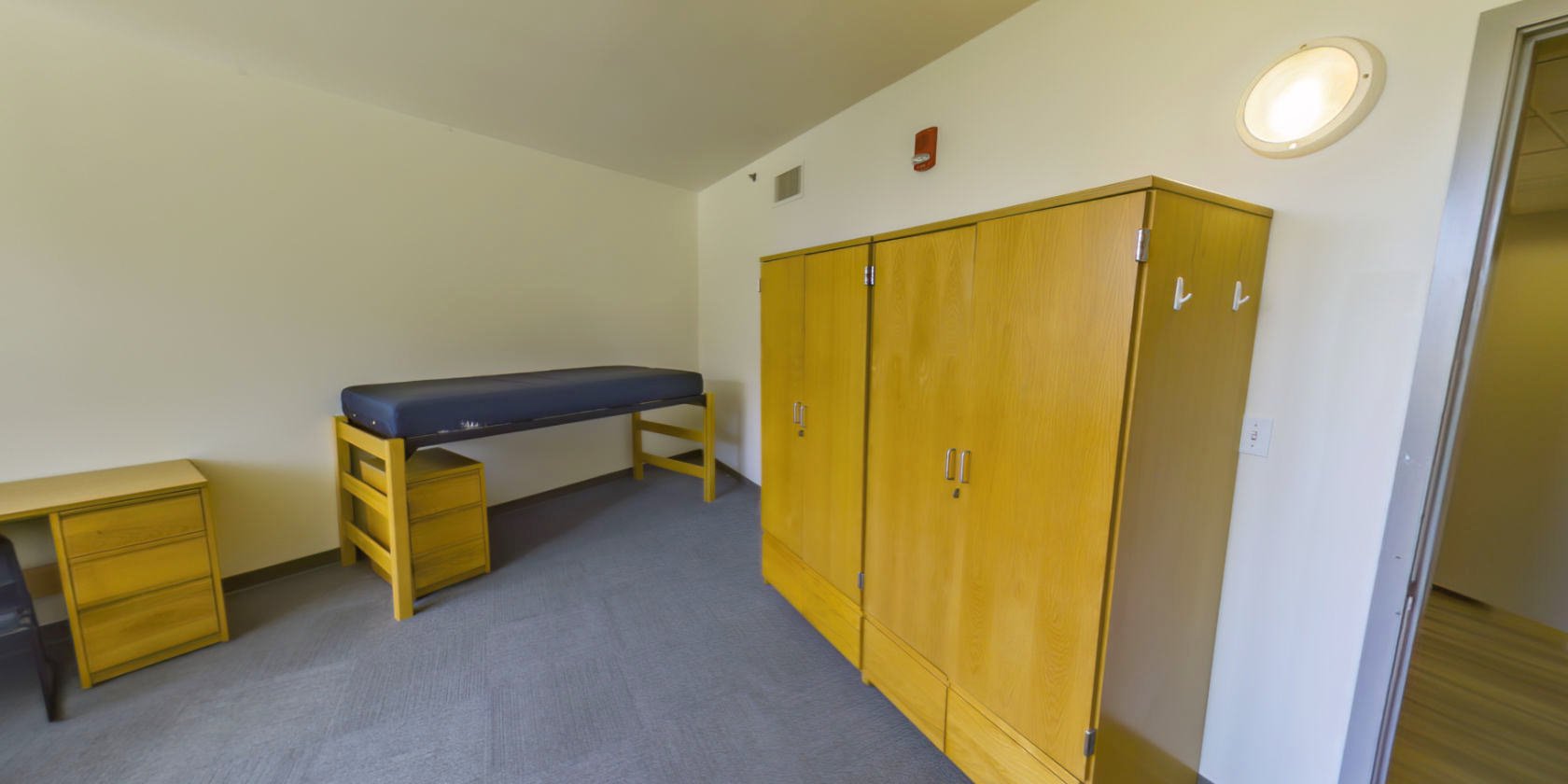 This side of the bedroom has a second single bed with space below for bedside storage. There are two sets of closet storage with small latches for padlocks near the entrance.