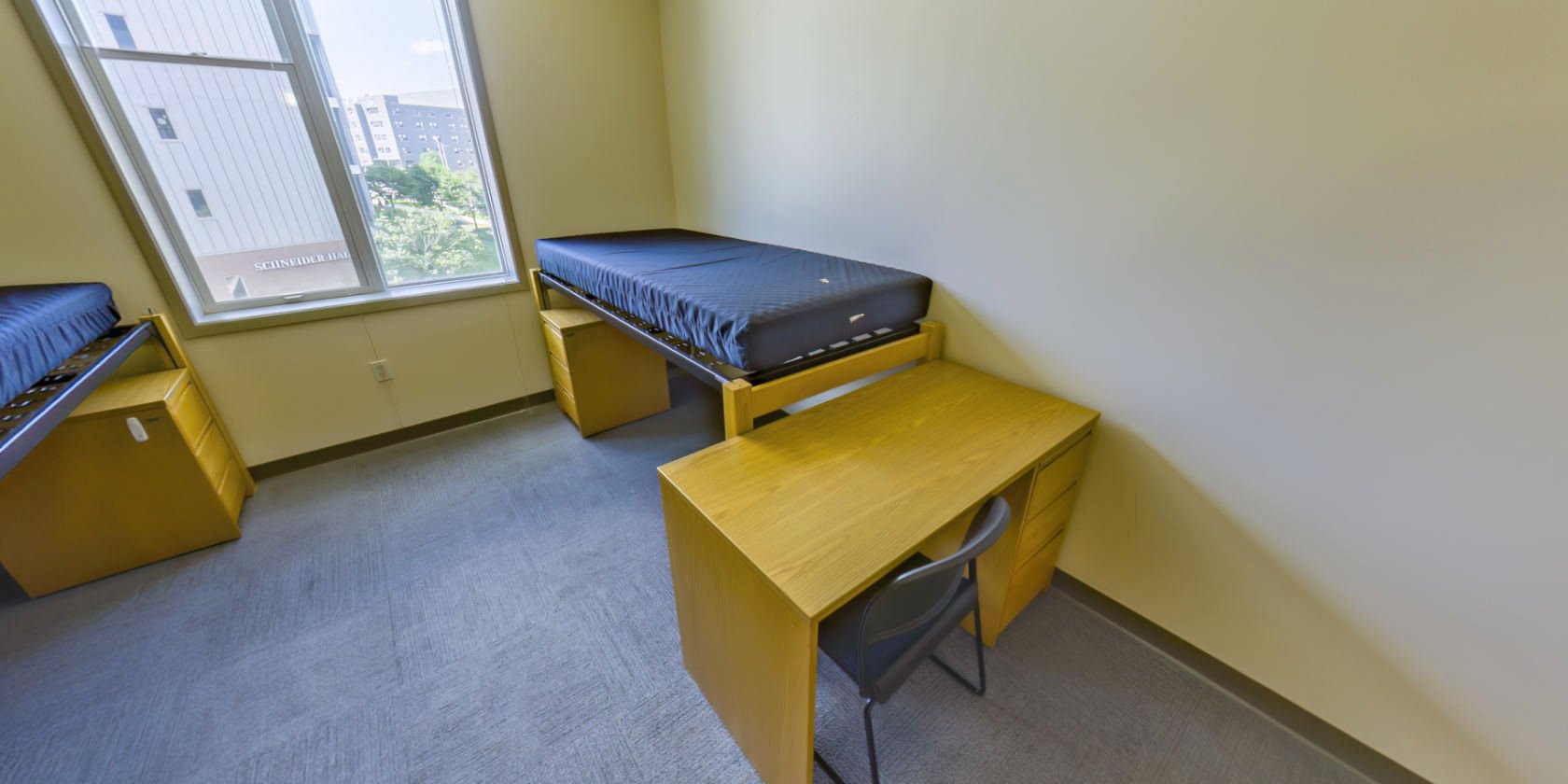 This side of the bedroom has a second single bed with space below for bedside storage and a desk with drawers.