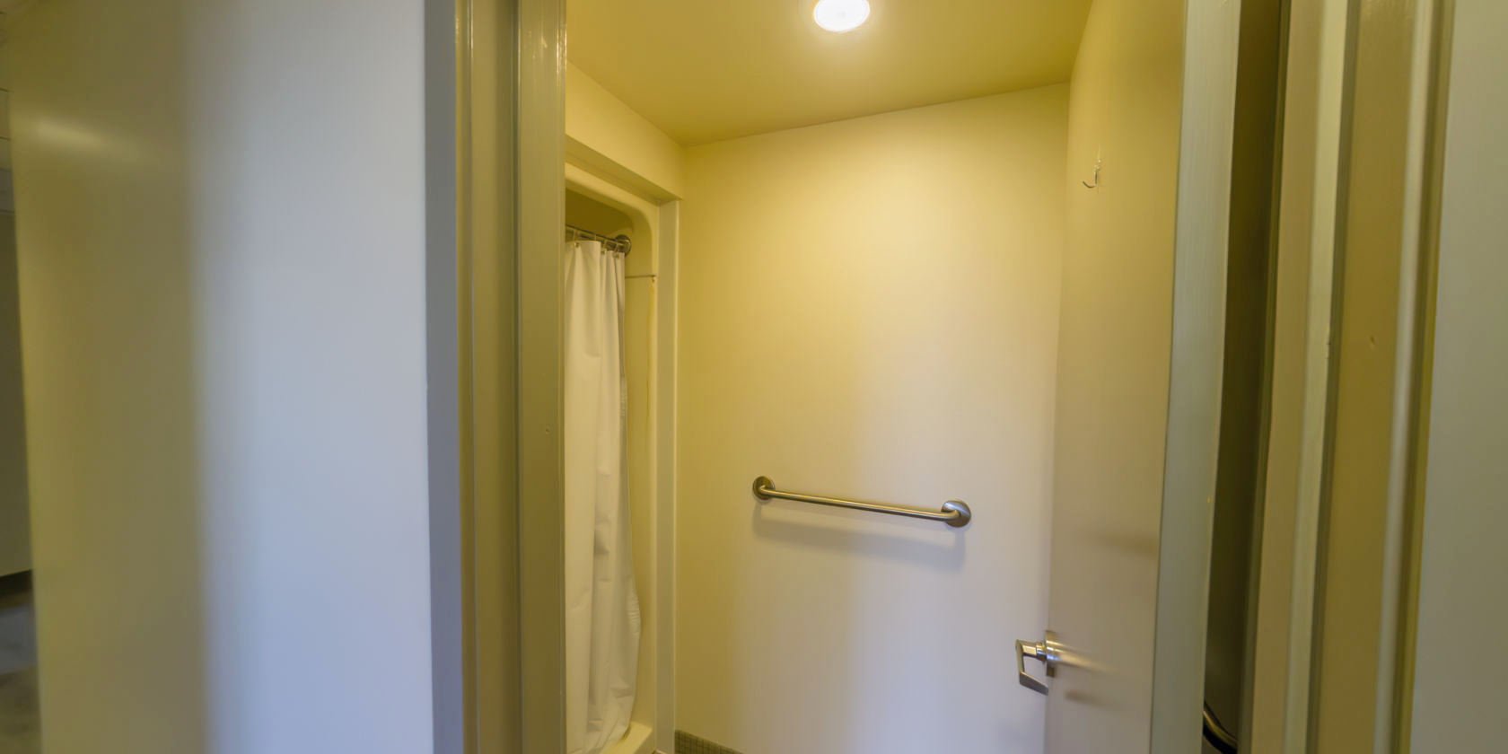 This side of the second hallway connects to a bathroom with a tiled floor and a walk-in shower.