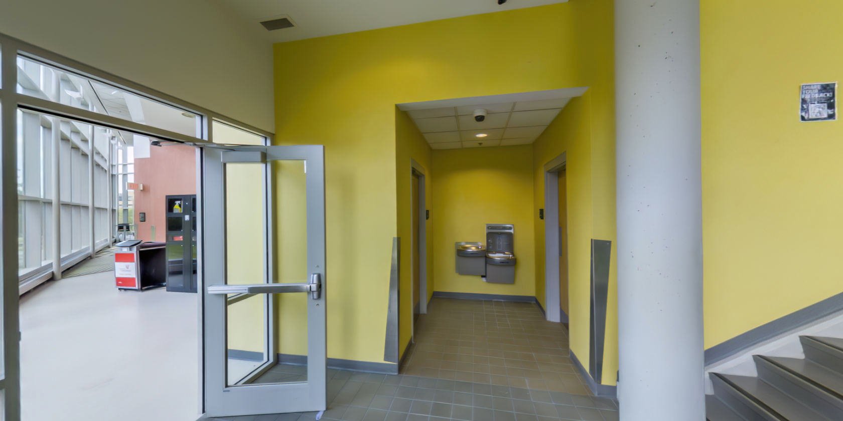 This side of the lobby has a tiled floor and access to public restrooms. There is a door with access to a breakout area.