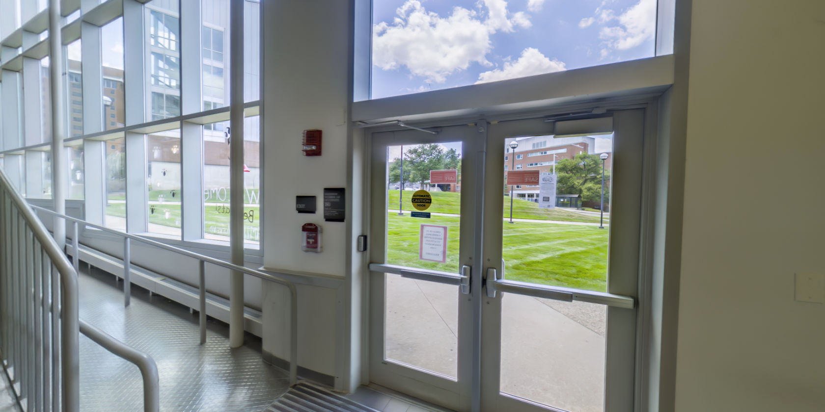 This side of the lobby has an entrance and windows with a view of the campus. There is a second non-slip accessible ramp, with handrails, leading up to the reception area.