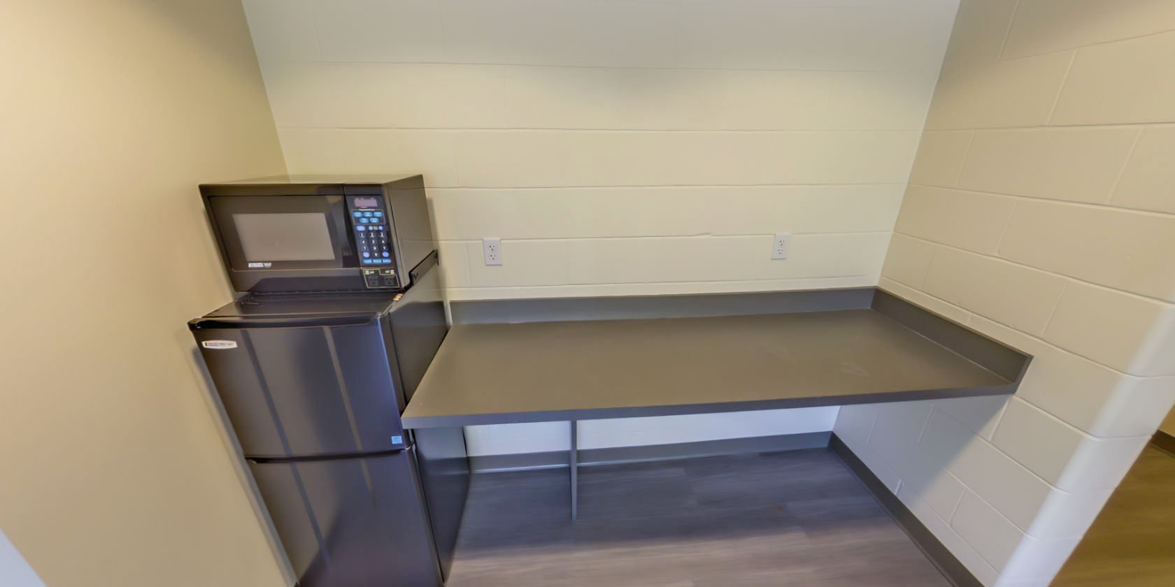 This side of the common area has countertop space and a small refrigerator with an attached microwave.