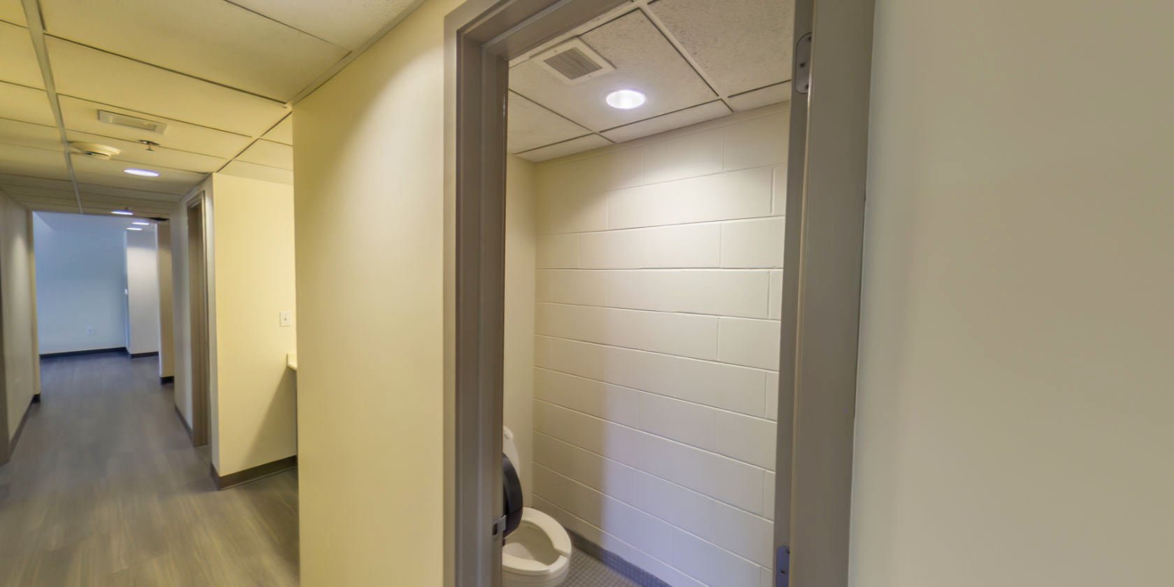 This side of the hallway connects to a tiled bathroom with a toilet.