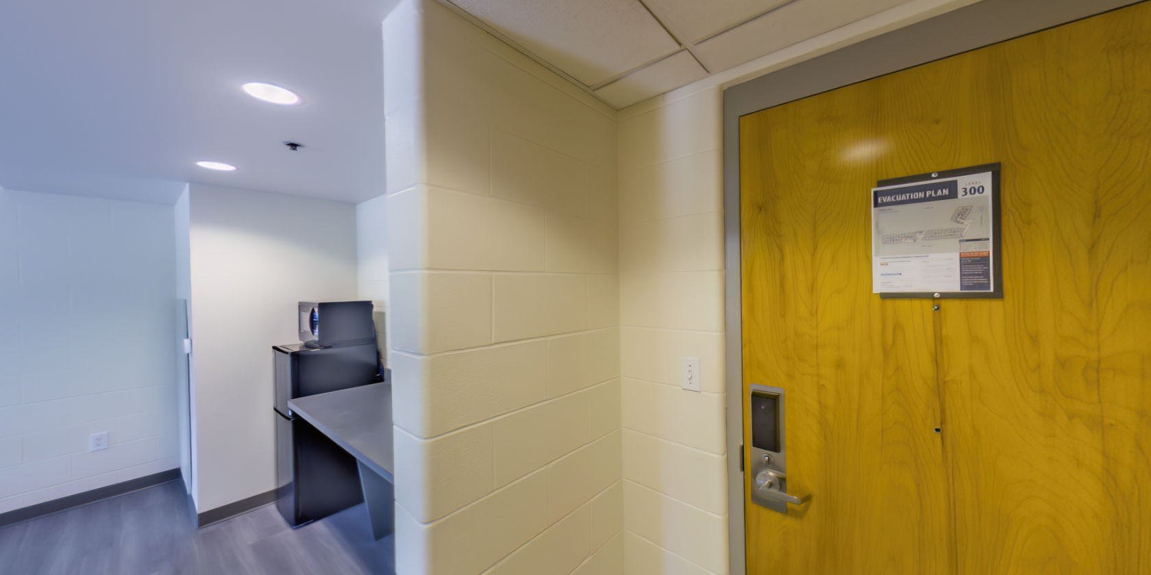 This virtual tour begins inside the entrance to a suite with laminate flooring and access to the common area.