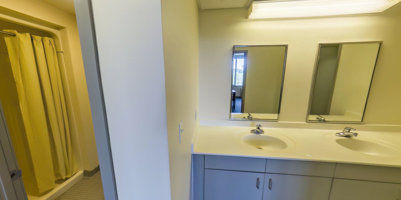 This side of the hallway has a tiled bathroom with a walk-in shower and access to an area with double vanities.