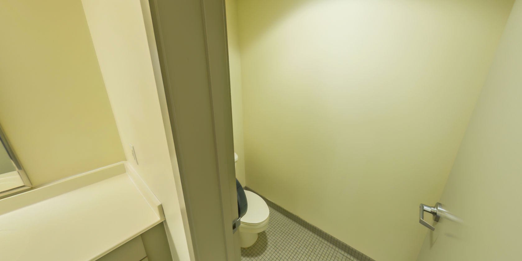 This side of the hallway connects to a tiled bathroom with a toilet.